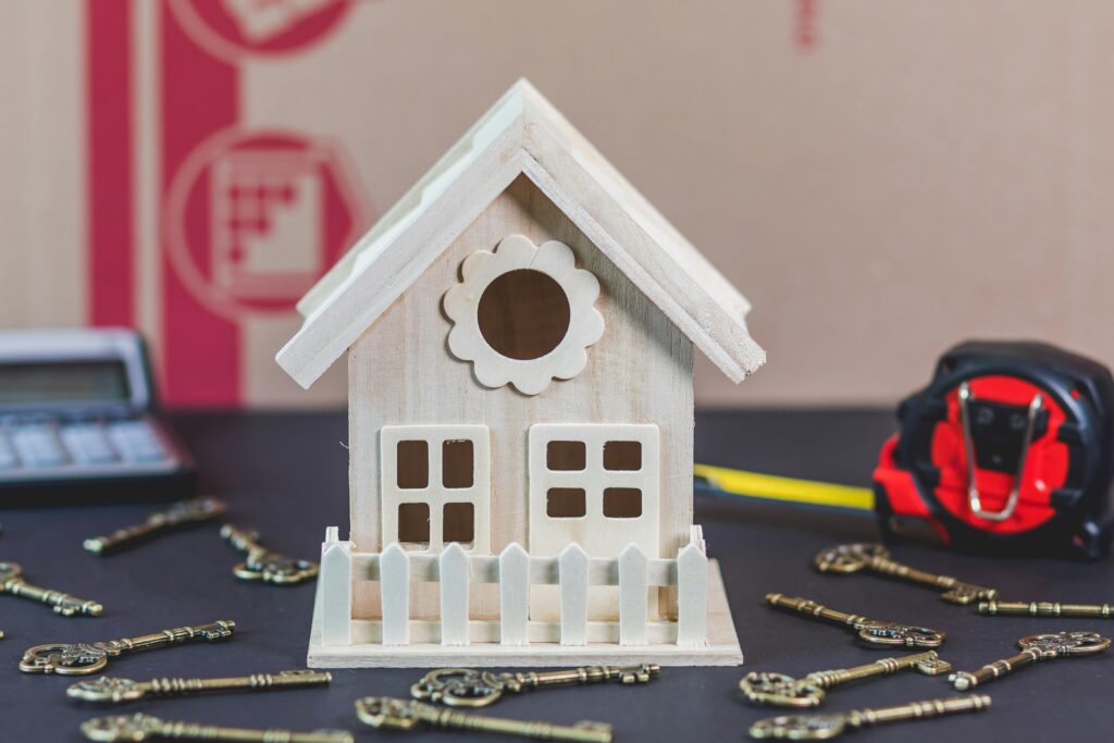 A charming wooden miniature house surrounded by antique-style keys, ideal for concepts of home ownership.
